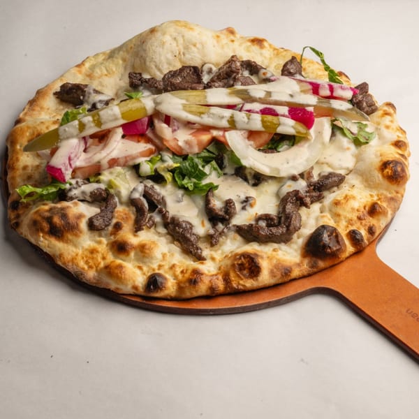 HOF Flatbreads' Lebanese flatbread topped with meat, lettuce, tomatoes, onions, pickles, and white sauce.