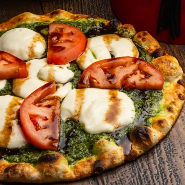 HOF Flatbreads pesto flatbread with fresh mozzarella, sliced tomatoes, and balsamic glaze.